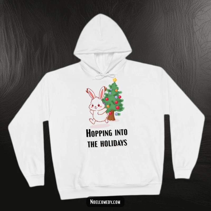 Funny Hoodie showcasing a fluffy bunny with antlers, mid-hop near a beautifully decorated evergreen, perfect for winter.