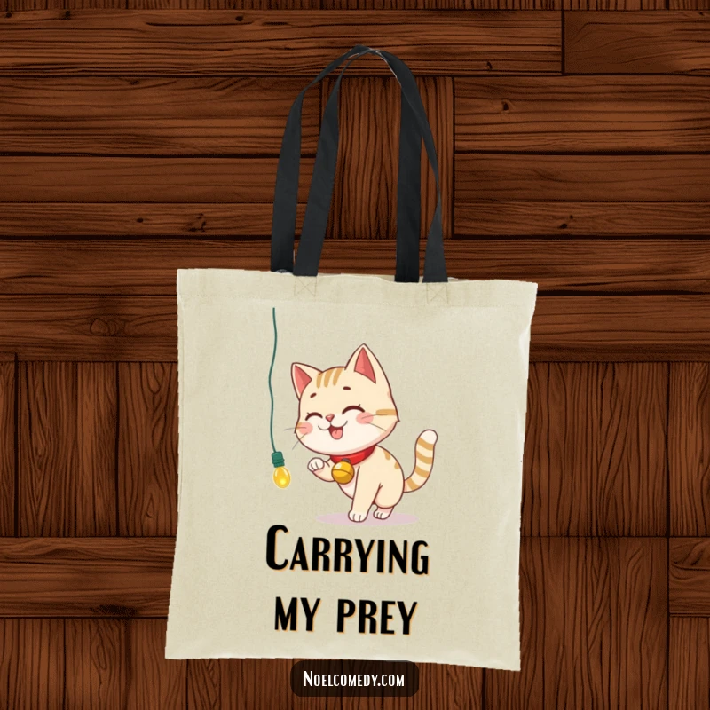 Funny Tote Bag showing a smiling cat with a bell collar chasing a dangling Christmas light, ideal for carrying.