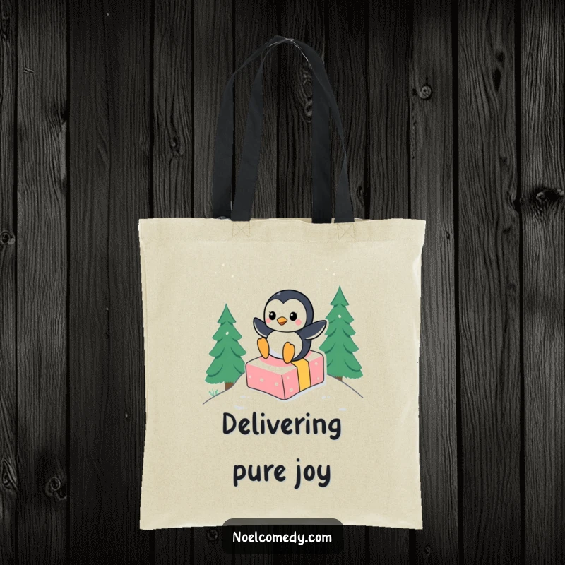 Funny tote bag showcasing a happy penguin character gleefully sliding down a snowy hill, riding on top of a festive gift box.